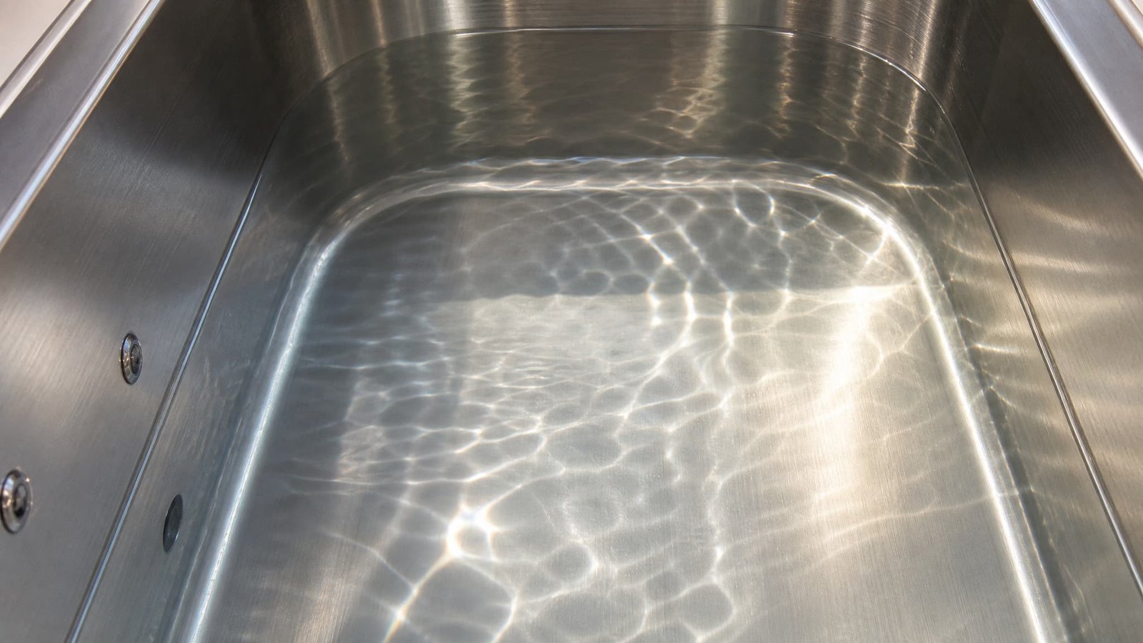 Close-up of a premium stainless steel cold plunge tub filled with clear water, ready for full-body ice bath