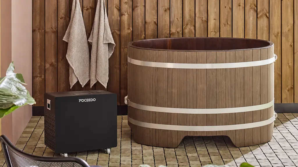A Blumenberg solid-wood plunge tub paired with a black FOCEEDO cold plunge chiller in a modern, sunlit wellness space.